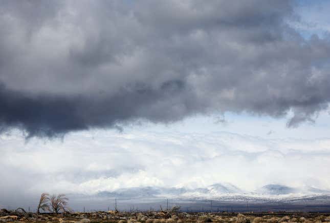 Storm clouds drop precipitation near snow-covered mountains during another winter storm in Southern California on March 01, 2023 near Lancaster, California.