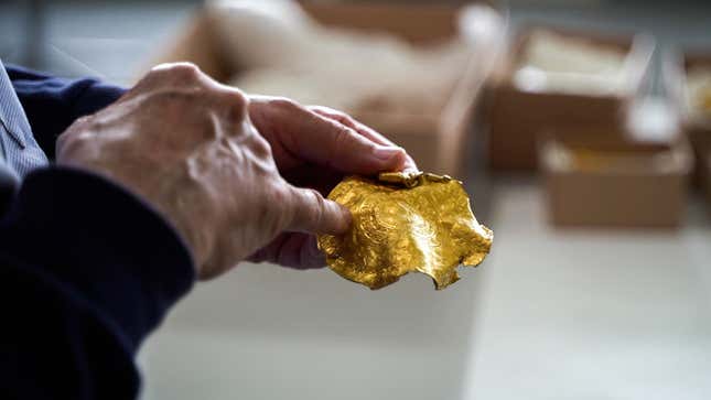 An investigator showing off one of the many items found in the gold hoard.