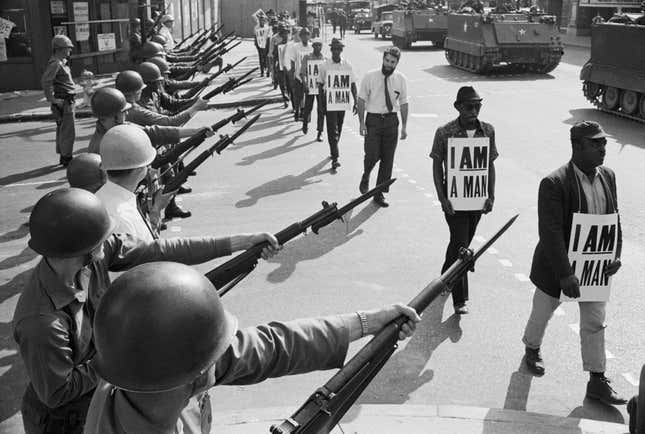 U.S. National Guard troops block off Beale Street as Civil Rights marchers wearing placards reading, “I AM A MAN” pass by on March 29, 1968. It was the third consecutive march held by the group in as many days. Rev. Martin Luther King, Jr., who had left town after the first march, would soon return and be assassinated.