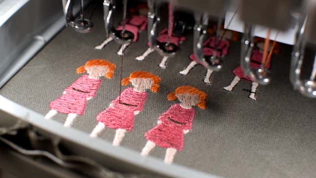 A machine embroiders three cartoon girls.
