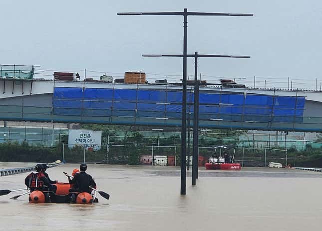 Emergency workers search for survivors along a road submerged by floodwaters leading to an underground tunnel in Cheongju, South Korea, on July 15, 2023. 