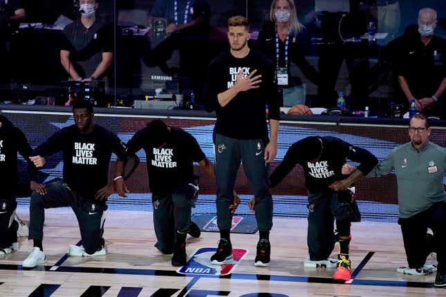 Meyers Leonard (then) of the Miami Heat stands during the National Anthem as his teammates take a knee.