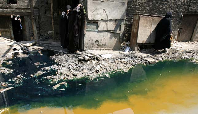 Women walk past tannery wastewater that is being pumped from a factory straight into the street of the Ain el Sirra district of Cairo June 14, 2007. Many people walk barefoot through the this district, seemingly not bothered by the waste, odours of chemicals and the smell of unprocessed skins. REUTERS/Steve Crisp (EGYPT) - GM1DVMFLURAA