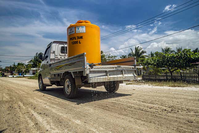 A truck carrying a water tank sprays the dirt road to reduce dust at Mangkupadi village near the construction site of the Kalimantan Industrial Park Indonesia (KIPI) in North Kalimantan, Indonesia on Thursday, Aug. 24, 2023. Residents hope the project may bring jobs, but worry they will lose their traditional livelihoods as fishermen, farmers and increasingly, eco-tourism hosts as dust and ash smother their fields. (AP Photo/Yusuf Wahil)