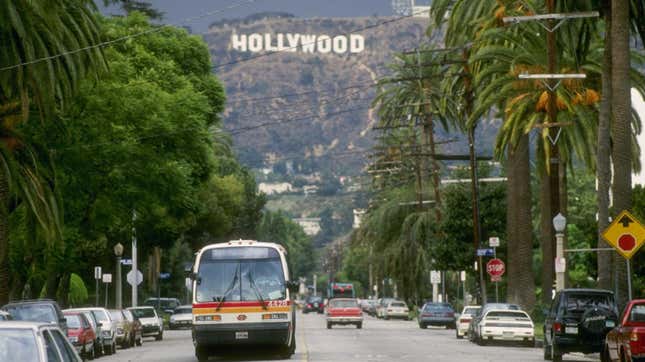 A street lined with trees with the Hollywood sign in the backround