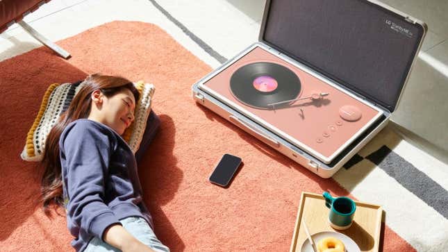 A person lying on a pillow next to the LG StanbyME with a virtual record player app on its screen that's laid flat.