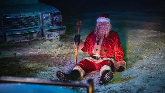 A dirty, beat-up Santa sits on the ground looking defeated