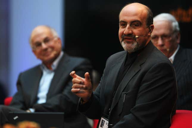 Nassim Taleb stands with a earpiece microphone speaking at a conference.