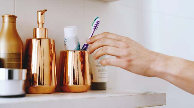 Woman's hand reaching for toothbrush in toothbrush holder