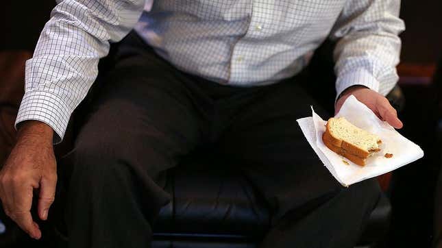 Man in business dress holding peanut butter sandwich
