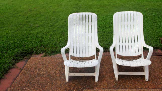 Two old white plastic lawn chairs that are scratched and dirty