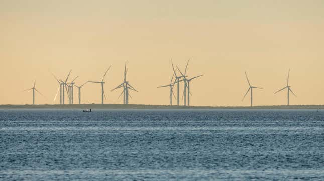 Fishermen in a boat on the Laguna Madre in front of giant wind generators on the mainland near Port Isabel, Texas.