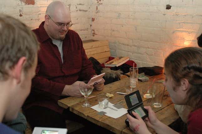 Mike Fahey of Kotaku looks down at his pink 3DS while sitting at a table.