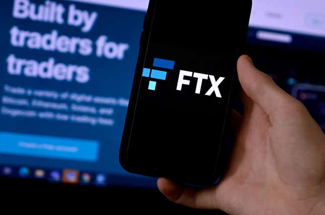 A phone with the logo FTX in front of a screen reading "Built by traders for traders."