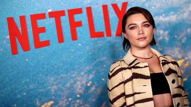 Florence Pugh with short dark hair and a striped jacket at a Netflix event.