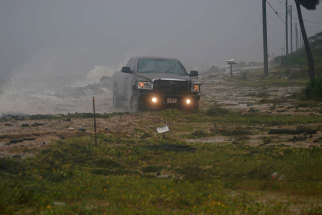 A truck drives along a road that has been washed out in Alligator Point, Florida.