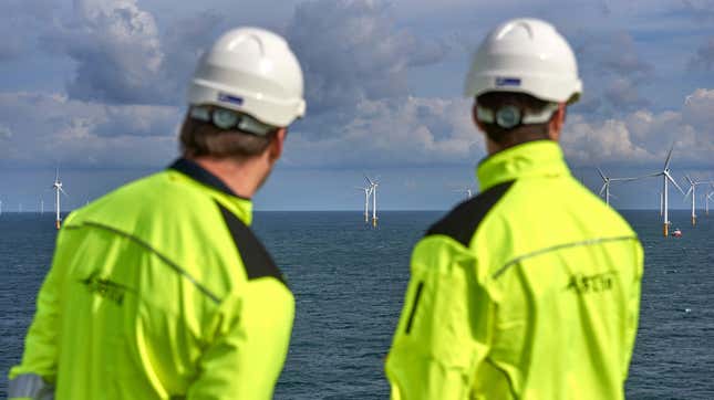 Two workers look at wind turbines as viewed from the Modular Offshore Grid in the North Sea off of the Belgian coast.