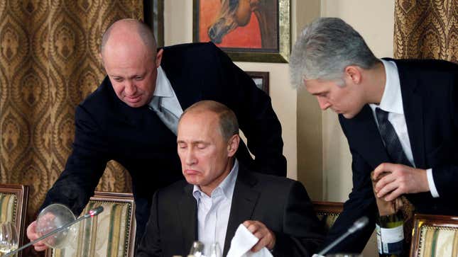 Prigozhin (L) assists Russian Prime Minister Vladimir Putin during a dinner with foreign scholars and journalists in 2011.