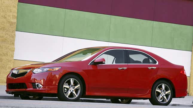 A photo of a red Acura TSX sedan parked on a street. 