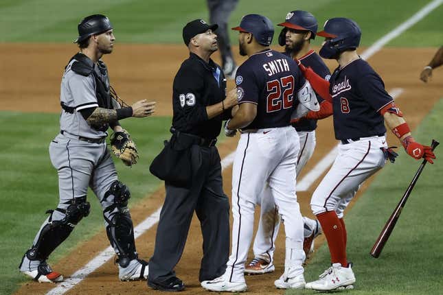 Sep 18, 2023; Washington, District of Columbia, USA; Washington Nationals first baseman Dominic Smith (22) is restrained from Chicago White Sox starting pitcher Mike Clevinger (not pictured) after hitting a home run by home plate umpire Will Little (93) as White Sox catcher Yasmani Grandal (24) steps in during the ninth inning at Nationals Park.