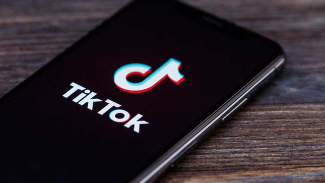 TikTok app open on a smartphone, lying on wood table