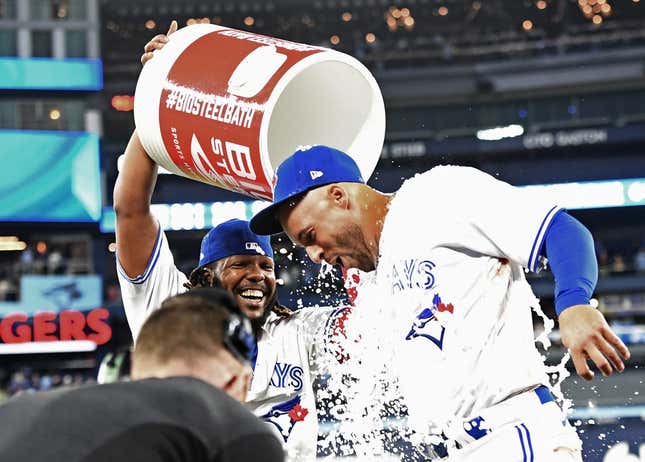 Apr 12, 2023; Toronto, Ontario, CAN;  Toronto Blue Jays right fielder George Springer (4) is doused with ice water by first baseman Vladimir Guerrero Jr. (27) after hitting a walkoff RBI single against the Detroit Tigers in the 10th  inning at Rogers Centre.