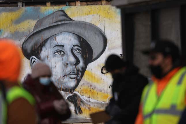 A mural featuring a portrait of civil rights icon Emmett Till looks out from an abandoned building front as volunteers gather nearby with family members of Tamiko Talbert-Fleming after passing out flyers in the Chicago Lawn neighborhood seeking information about her murder on January 19, 2022, in Chicago, Illinois. 