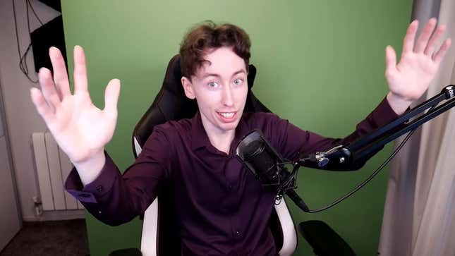 Daniel Condren is shown sitting in front of a green screen and talking into a microphone with his hands in the air.