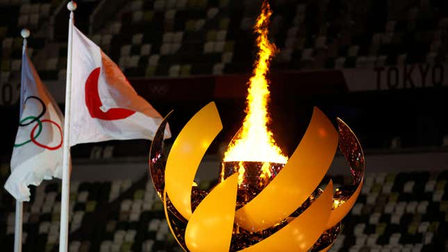 A picture shows the Olympic Flame and Cauldron next to the Japanese and Olympic flags during the opening ceremony of the Tokyo 2020 Olympic Games,