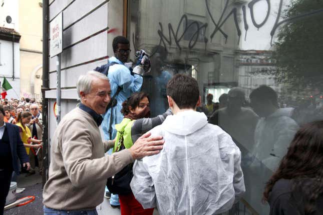 Milan Mayor Giuliano Pisapia (L) speaks to people cleaning a shop window during the march “Nobody touch Milan,” which was organized in response to the No Expo clashes.