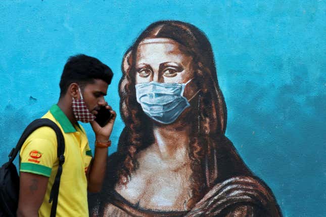 A man walks past a mural depicting the "Mona Lisa" wearing a face mask amidst the spread of the coronavirus disease (COVID-19), in Mumbai