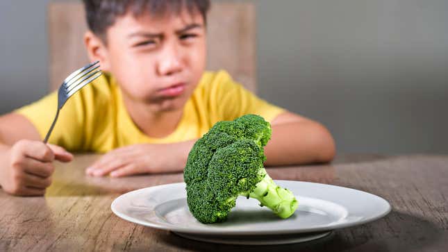 Child looking disgusted by a plate of broccoli