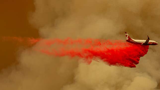 A photo of a Boeing 737 dropping fire retardant on a forrest fire. 