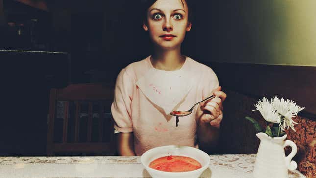 Woman eating soup with frightened expression