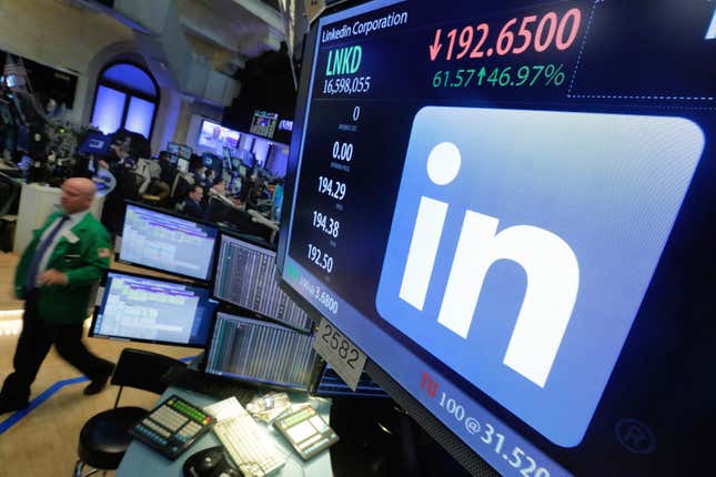 The LinkedIn logo at the New York stock exchange on a monitor with people walking by.