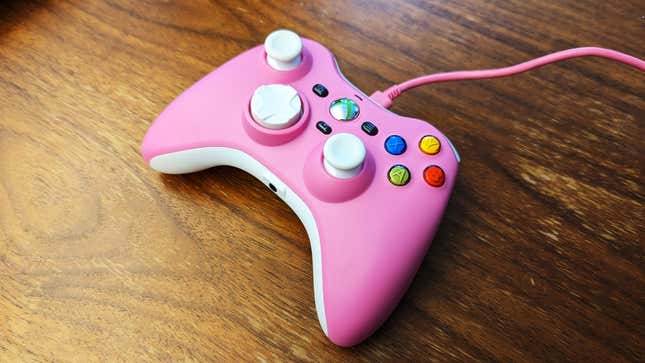 A pink Xbox 360 replica controller sits on a wooden table.
