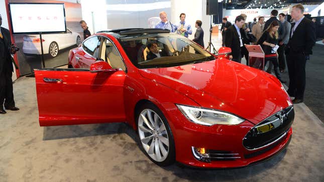 An early red Tesla Model S sits on an auto show floor