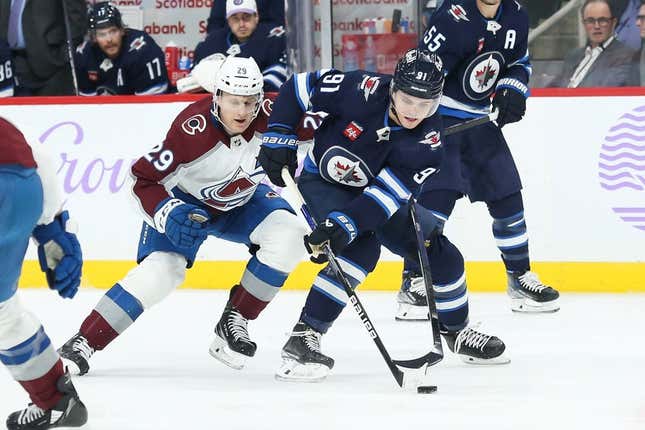 Nov 29, 2022; Winnipeg, Manitoba, CAN;  Winnipeg Jets forward Cole Perfetti (91) battles Colorado Avalanche forward Nathan MacKinnon (29) for the puck during the second period at Canada Life Centre.