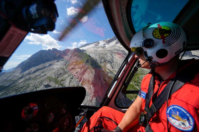 A rescuer pilots a helicopter to look for survivors.