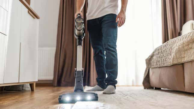 Man vacuuming bedroom rug