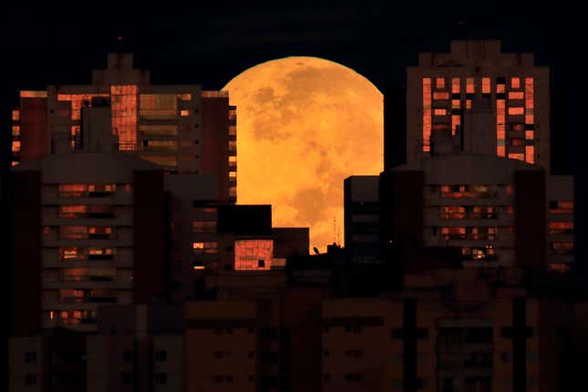The moon is partially covered by buildings in Brasilia, Brazil, at the start of a total lunar eclipse early Wednesday, May 26, 2021. Wednesday’s eclipse is the first in more than two years and coincides with a supermoon.
