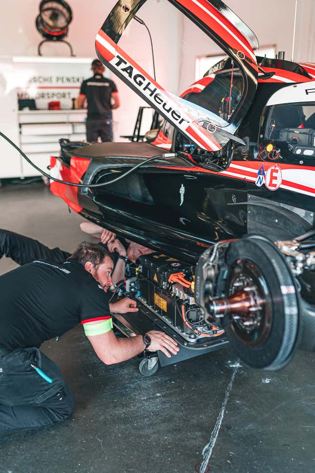 Porsche team mechanic pushing a cart holding the Williams battery power unit to install it into the 963 race car