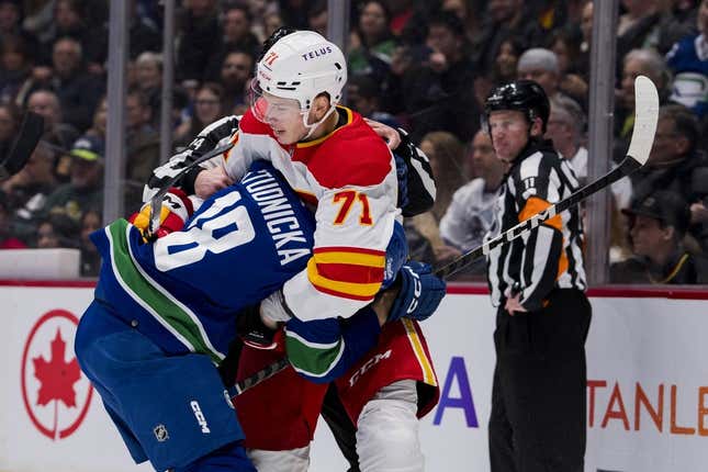 Mar 31, 2023; Vancouver, British Columbia, CAN; Calgary Flames forward Walker Duehr (71) wrestles with Vancouver Canucks forward Jack Studnicka (18) in the second period at Rogers Arena.