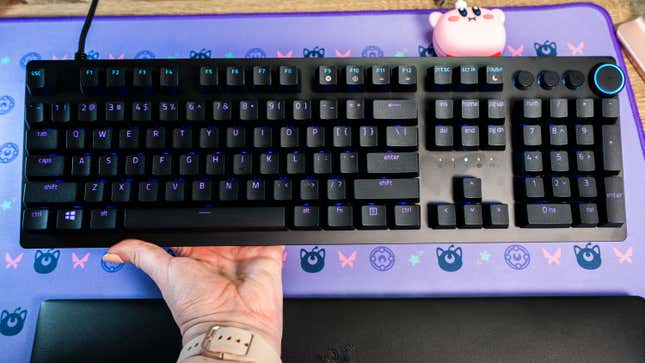 A photo of a hand holding up the Razer Huntsman V2 mechanical keyboard