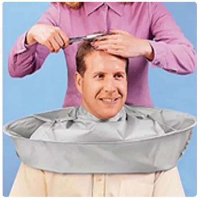 A man getting a haricut with a cape on him.