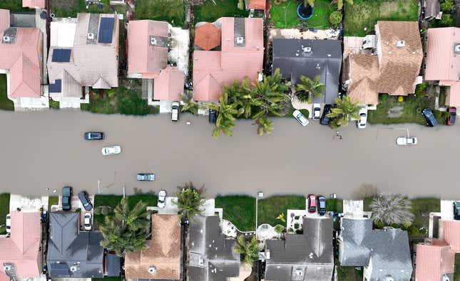 In an aerial view, homes are seen surrounded by floodwaters on January 11, 2023 in Planada, California. 