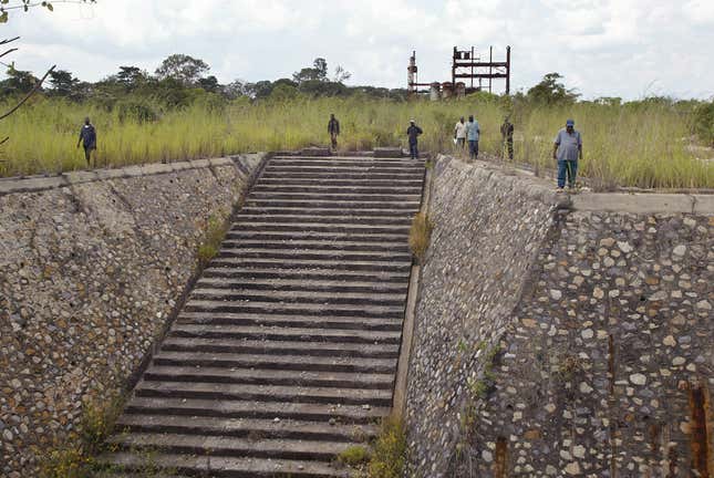 Men walk around the area where uranium was once mined, at the Shinkolobwe Cobalt mine