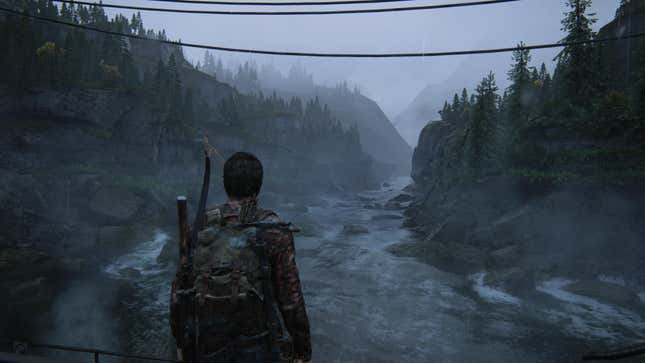 Joel looks out at rocky, tree-covered hills and a wide river in a shot from the game The Last of Us.