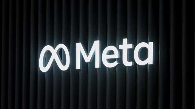 A glowing Meta logo is displayed in front of a black wall. 