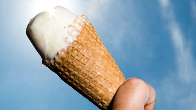 Melting vanilla ice cream cone with blue sky in background